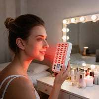 Woman holding the illuminated YA20-2W7 panel near her face during an at-home red light therapy routine