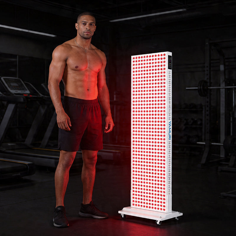 Athletic man standing beside large red light therapy panel in gym setting