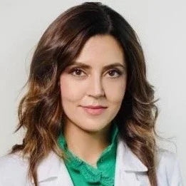 Woman in white lab coat and green shirt, representing professional red light therapy expertise